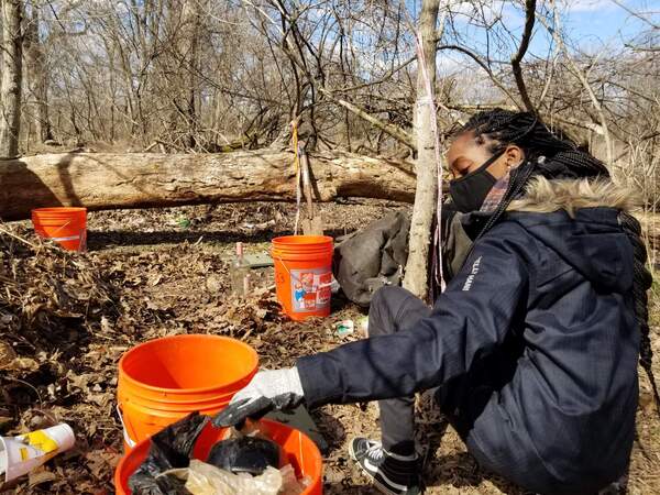 Team member Sahmira is sorting trash into orange buckets